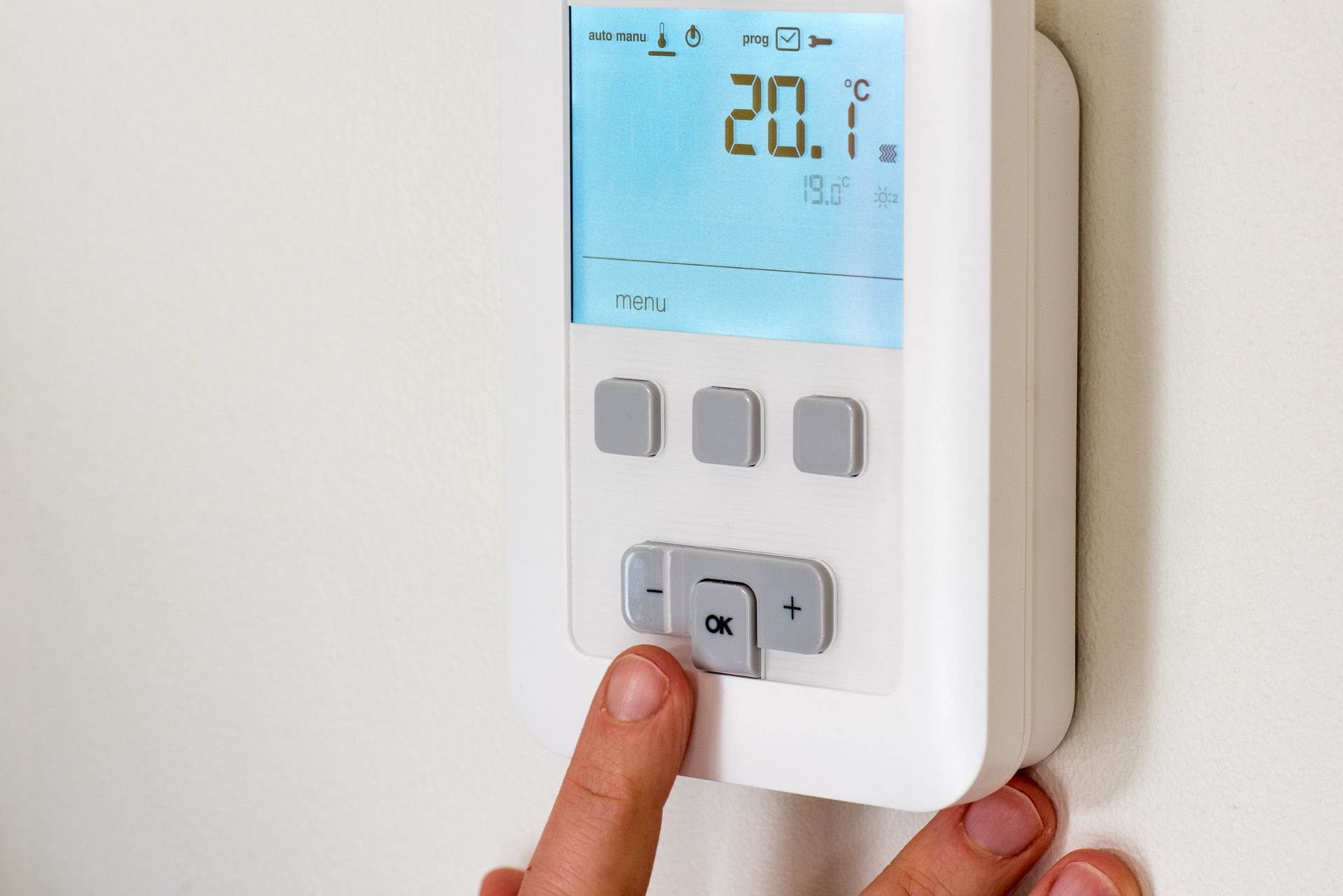 Una persona está presionando un botón en un termostato que marca 20,1 grados.icono