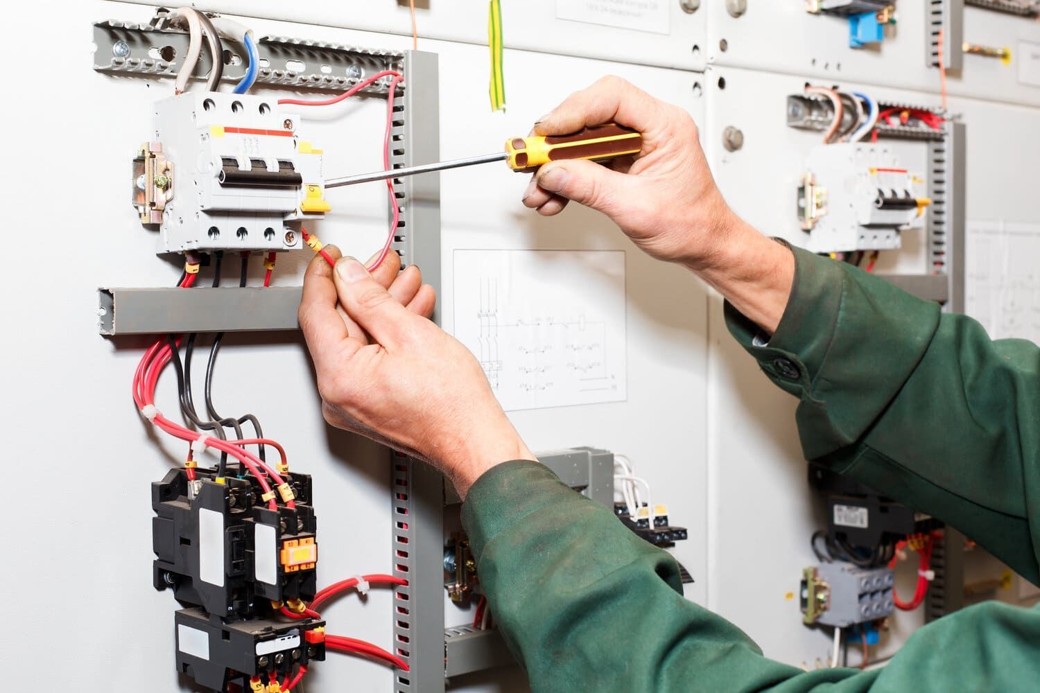 Un hombre está trabajando en un panel eléctrico con un destornillador.