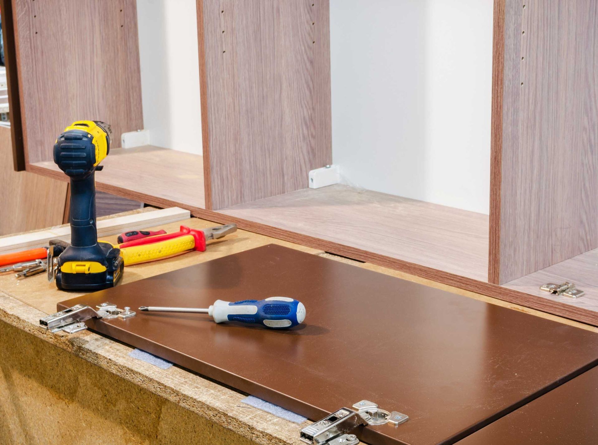 Un taladro está sobre una mesa de madera al lado de un destornillador.