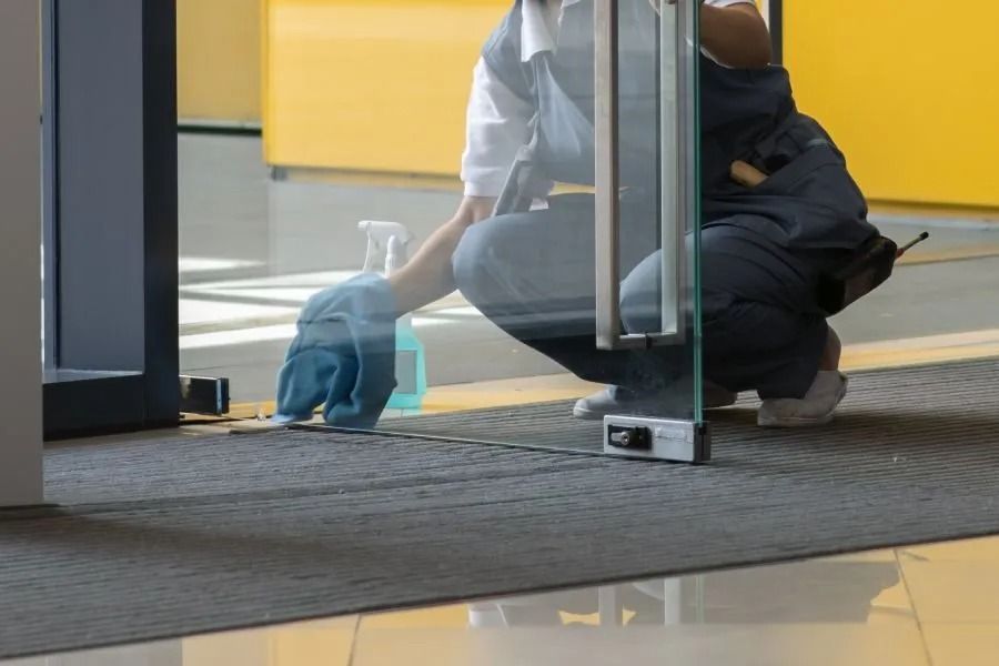 Person reinigt Glastür Person reinigt Glastür