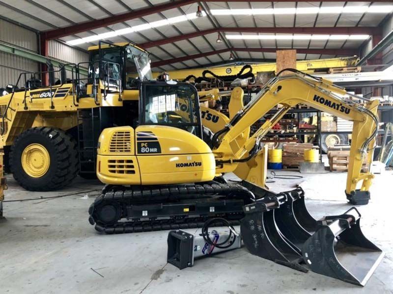 Una excavadora Komatsu amarilla está estacionada en un almacén.