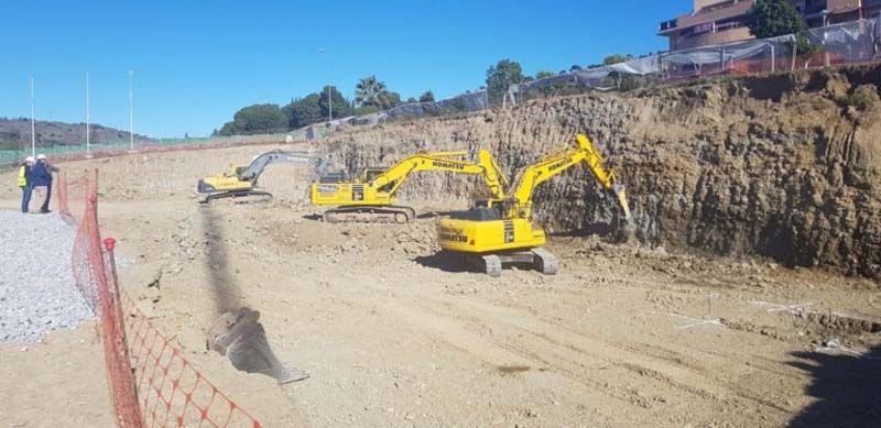 Un grupo de excavadoras amarillas está trabajando en un sitio de construcción.