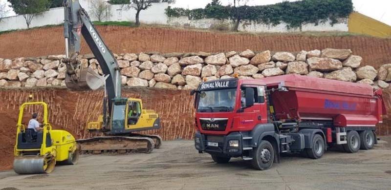 Un camión rojo está estacionado al lado de una excavadora amarilla.