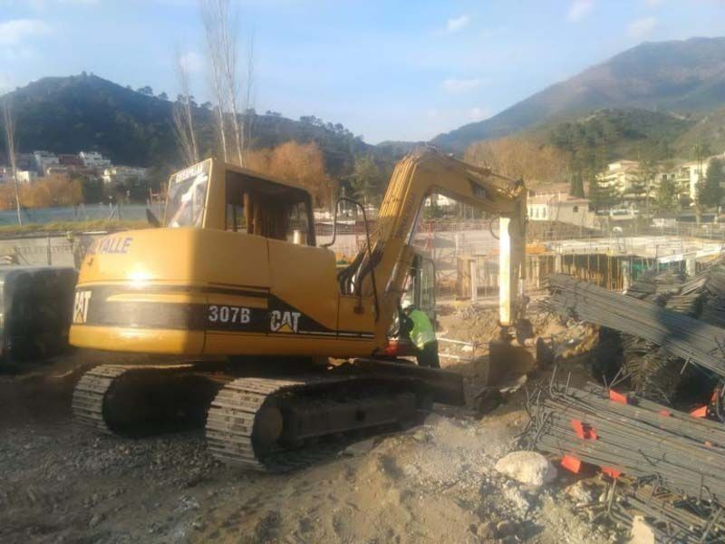 Una excavadora amarilla está sentada encima de un campo de tierra.
