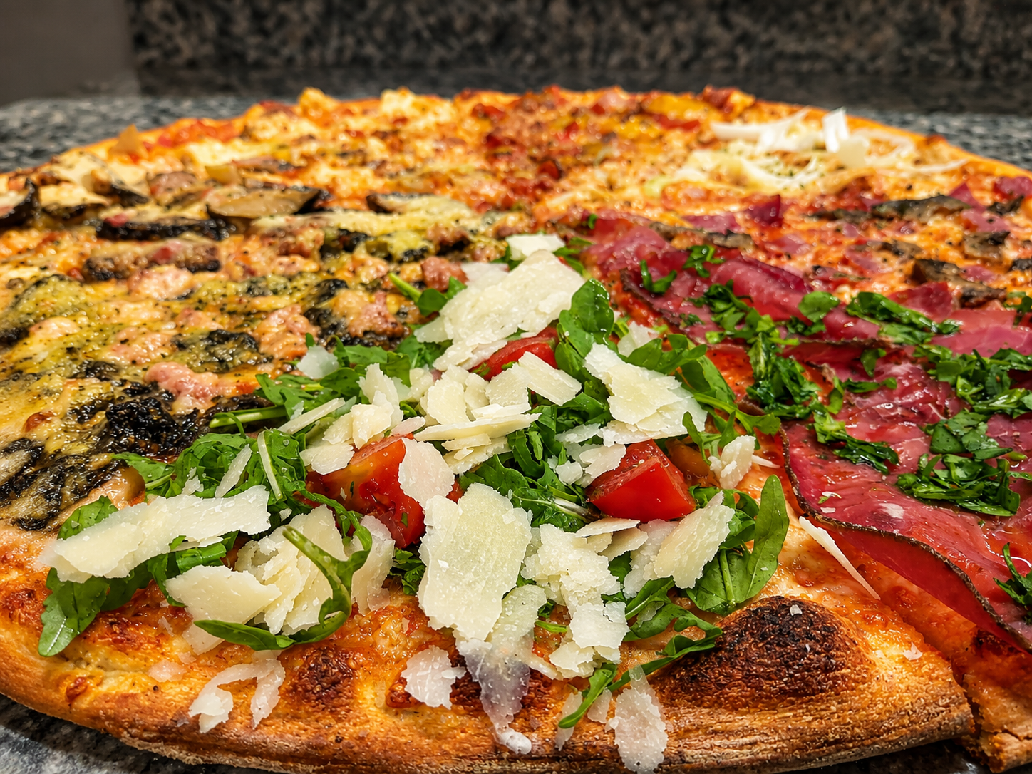 Primo piano di una pizza con quattro ingredienti: formaggio, verdure, carne rossa ed erbe aromatiche su una crosta croccante.