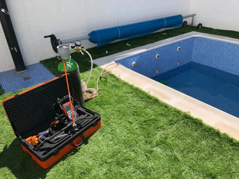 Una botella de gas está junto a una piscina.