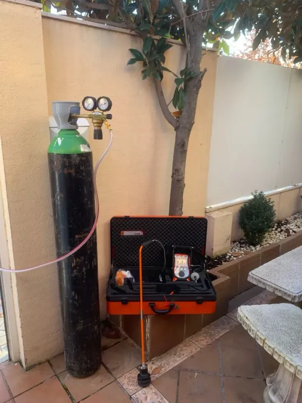 Hay un cilindro de gas junto a una caja de herramientas en un patio.