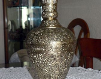 Un gran jarrón de latón está sobre una mesa.