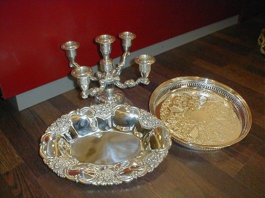 Sobre una mesa de madera hay un plato de plata y un candelabro de plata.