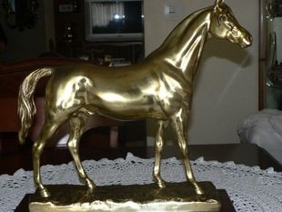 Una estatua de bronce de un caballo de pie sobre una base de madera.