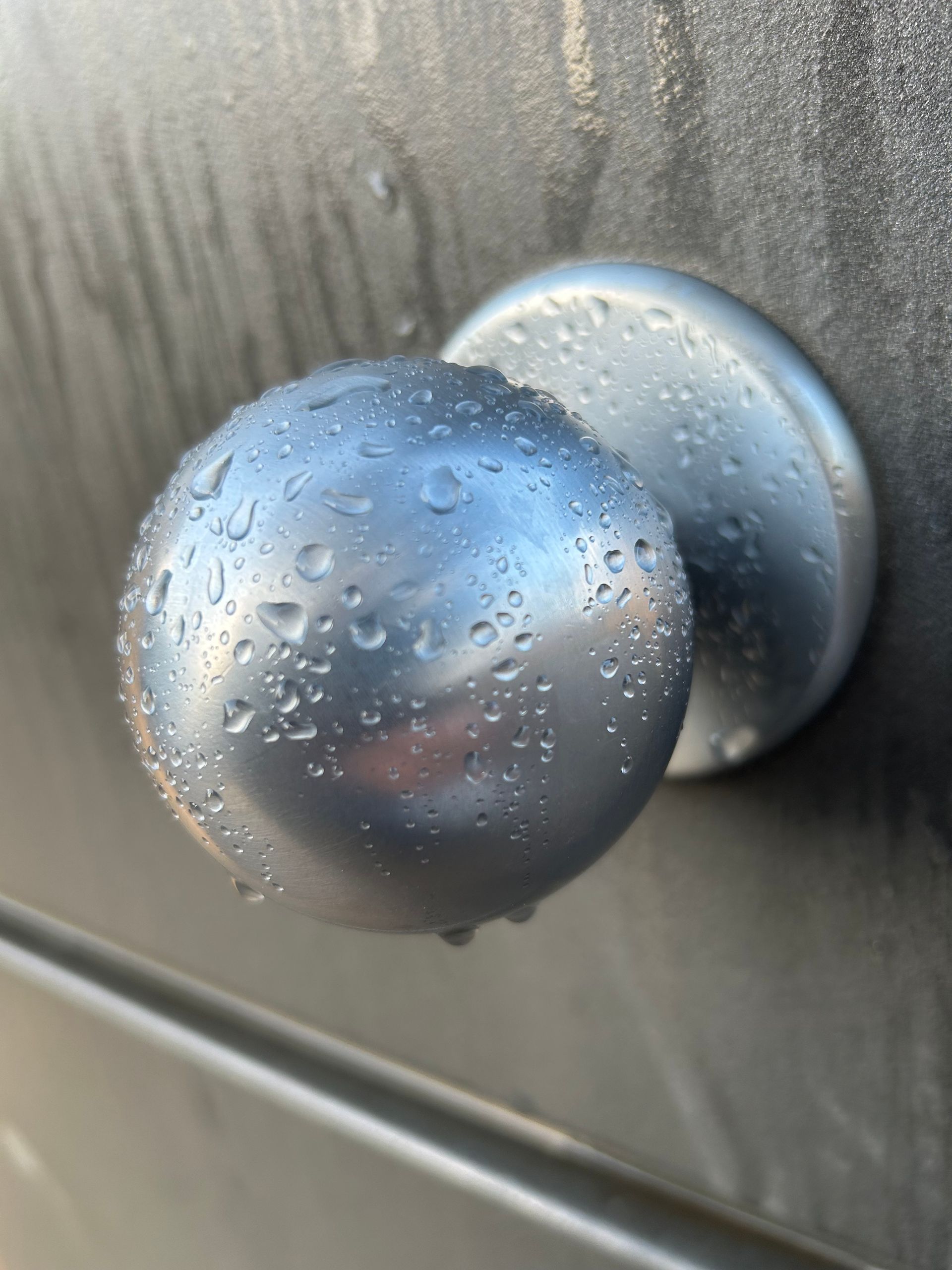 Un primer plano de un pomo de puerta con gotas de agua sobre él.