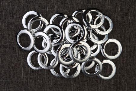 Un montón de anillos de plata se encuentran sobre una superficie negra.