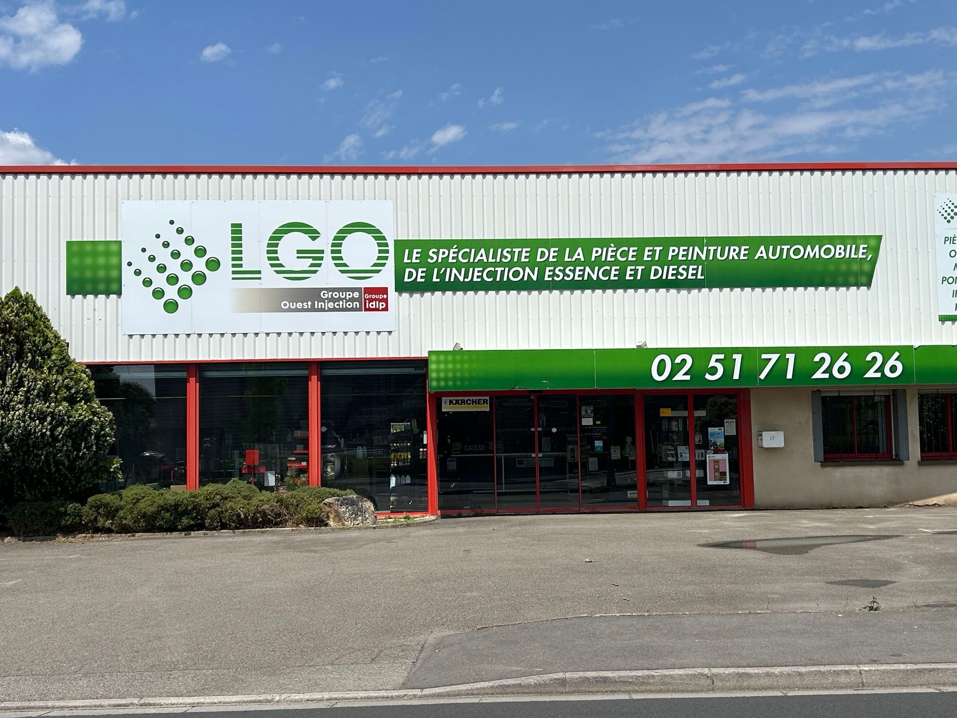 Façade du magasin LGO avec enseigne verte et entrée encadrée de rouge sous un ciel bleu