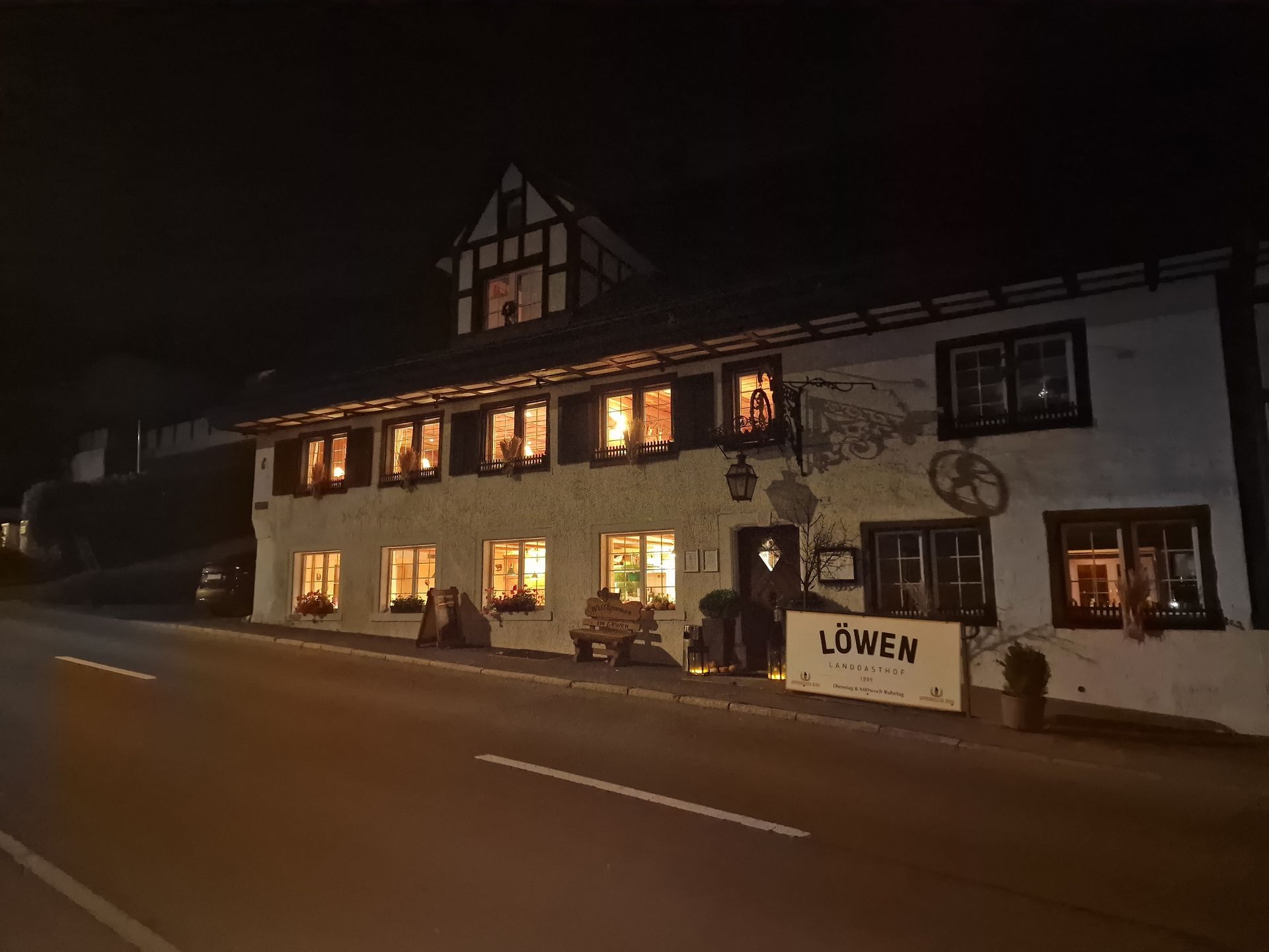 Ein zweistöckiges, nachts beleuchtetes Gebäude mit Fachwerkfassade. Ein Schild mit der Aufschrift „Lowen“