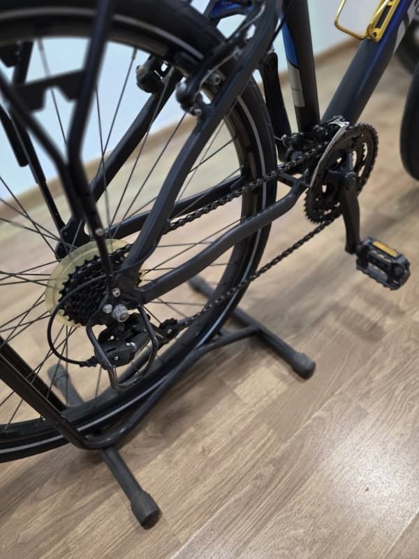 Una bicicleta está colocada sobre un soporte sobre un suelo de madera.