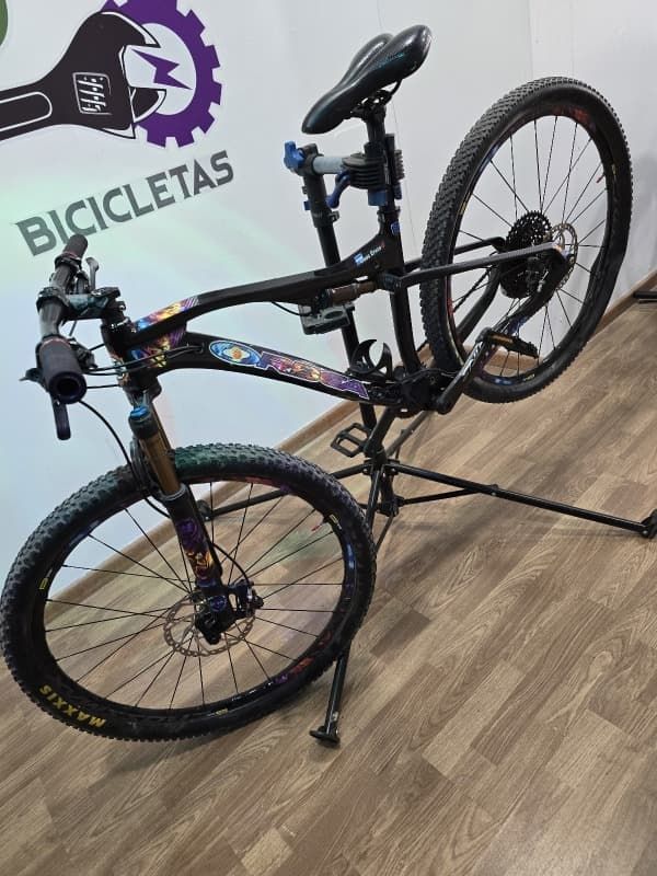 Una bicicleta está sentada en un soporte frente a un cartel que dice bicicletas