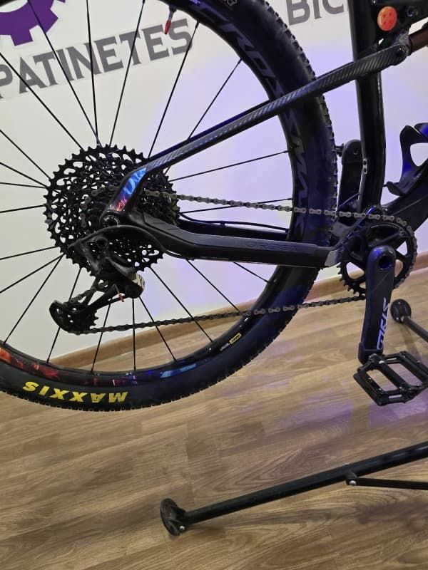 Una bicicleta está sentada sobre un piso de madera frente a un cartel que dice patinetes