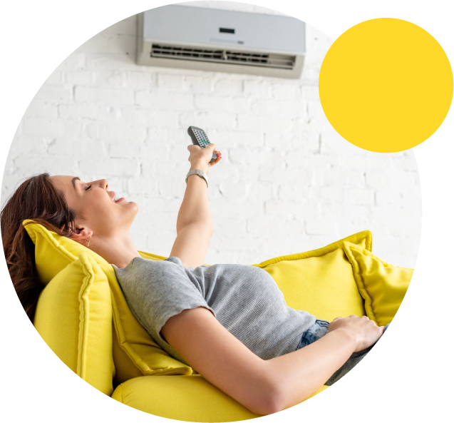Femme allongée dans son canapé réglant sa clim avec une télécommande
