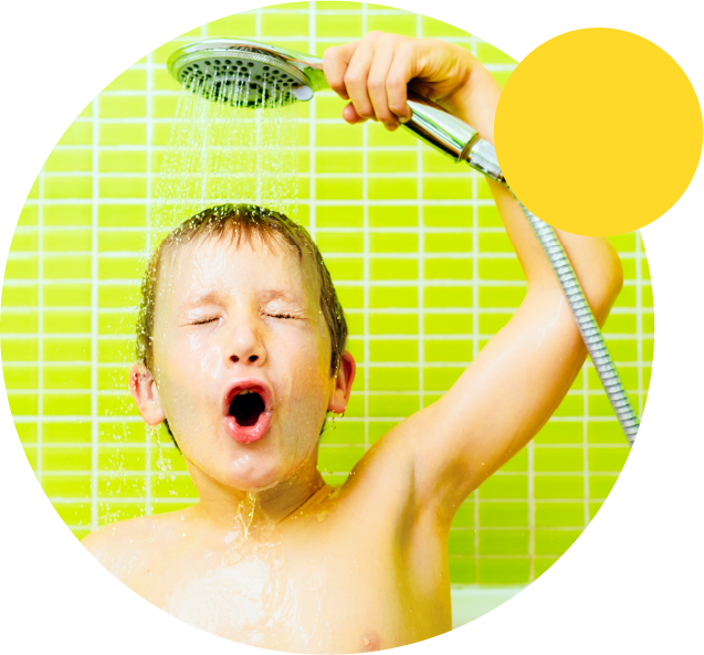 Petit garçon dans sa baignoire avec le pommeau de douche au dessus de sa tête
