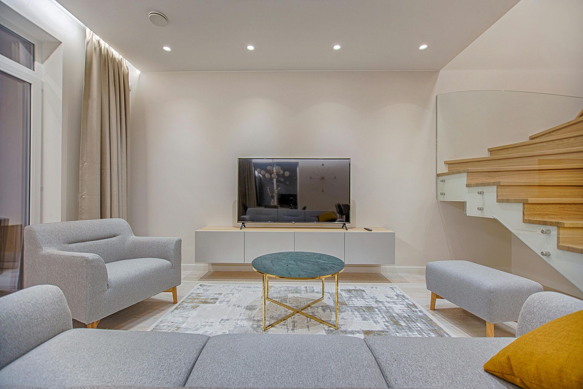 Una sala de estar con sofá, sillas, mesa y televisión.