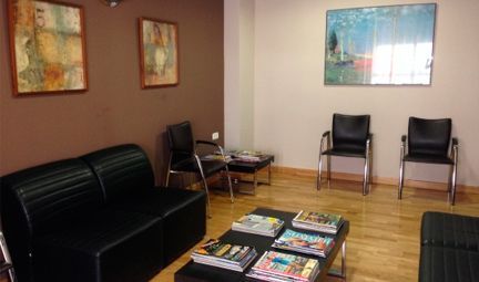 Una sala de espera con un sofá y sillas y una mesa con revistas encima.
