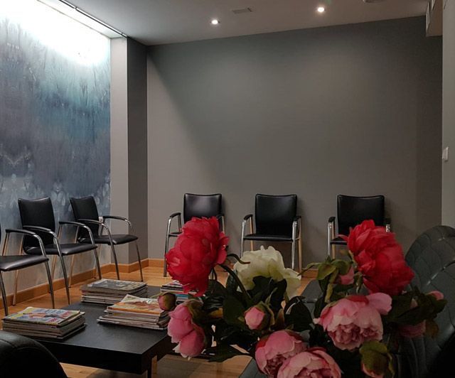 Una sala de espera con sillas y una mesa con flores.