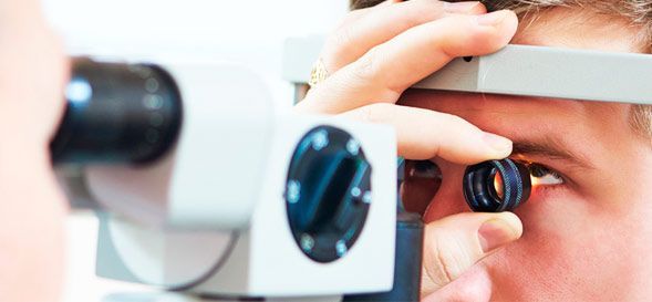 Un hombre mira su ojo a través de un microscopio.