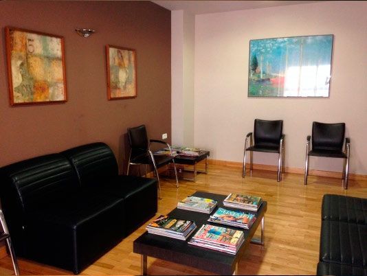 Una sala de espera con un sofá, una mesa y sillas.