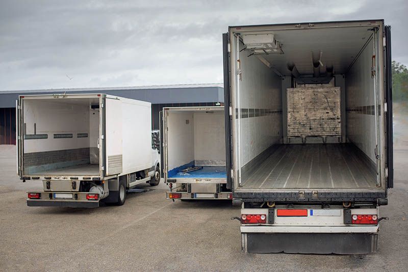 Auf einem Parkplatz stehen drei Kühllastwagen nebeneinander.