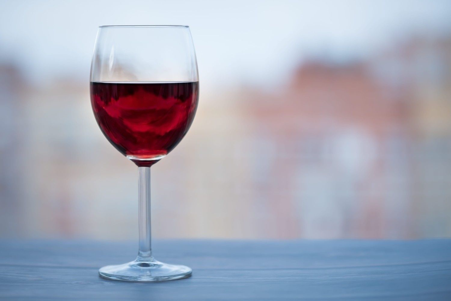 Una copa de vino tinto sobre una mesa con un fondo desenfocado.