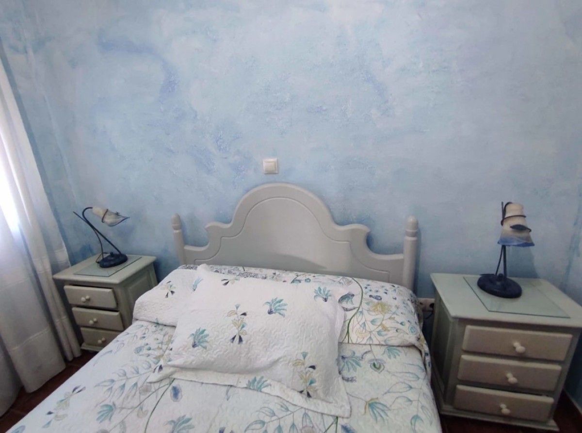 Dormitorio azul con una cama bien hecha y mesitas de noche a juego.