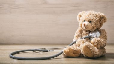 Rückansicht Mutter mit zwei Kindern im Schneidersitz