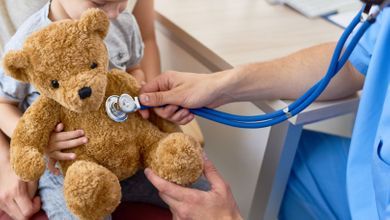 Rückansicht Mutter mit zwei Kindern im Schneidersitz