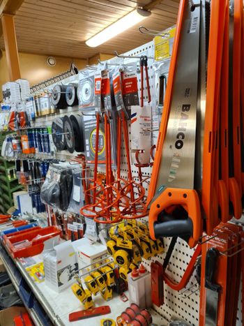 Rautakaupan käytävä, jonka hyllyillä on käsisahoja, puristimia ja oransseja työkaluja
