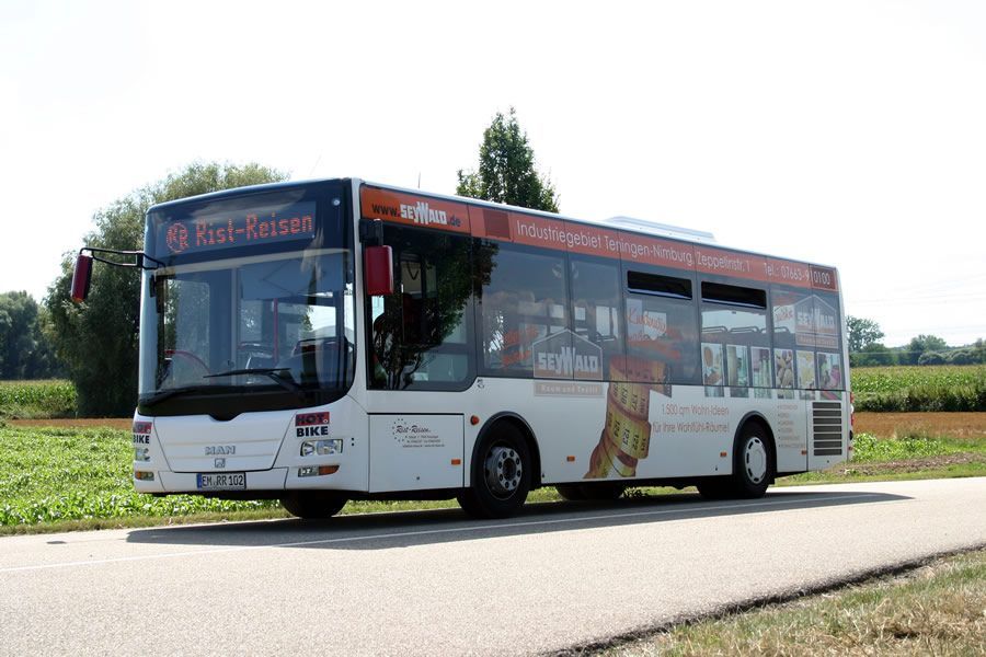 Ein weiß-orangefarbener Bus fährt eine Straße entlang.
