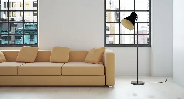 Un sofá color canela y una lámpara negra en una habitación moderna con vistas a la ciudad a través de las ventanas.