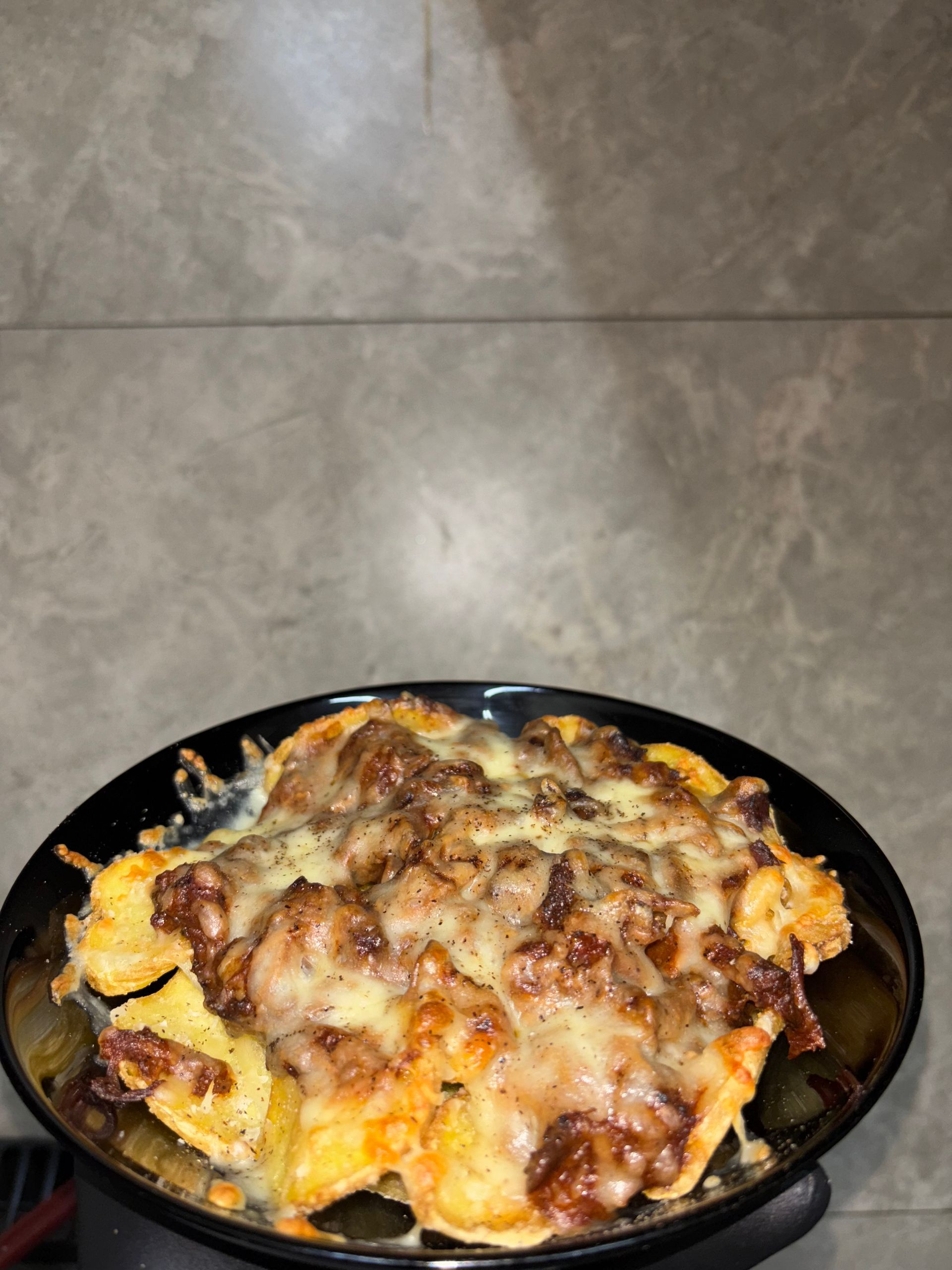 Hay un recipiente con ketchup al lado de un plato de comida.