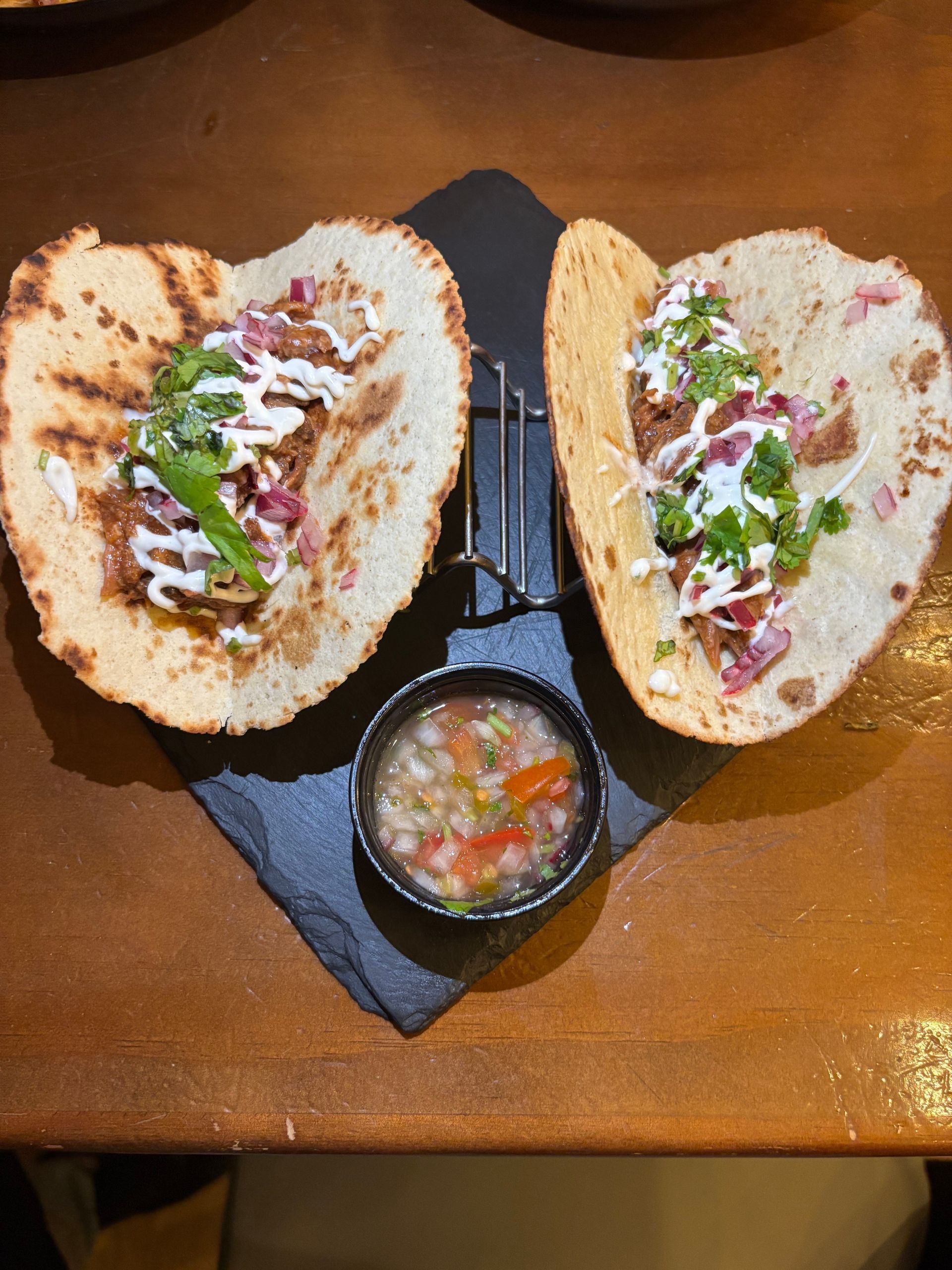 Un plato blanco cubierto con un gofre y helado sobre una mesa de madera.