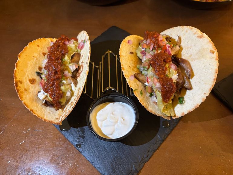 Una persona está poniendo queso en una hamburguesa sobre un pan.