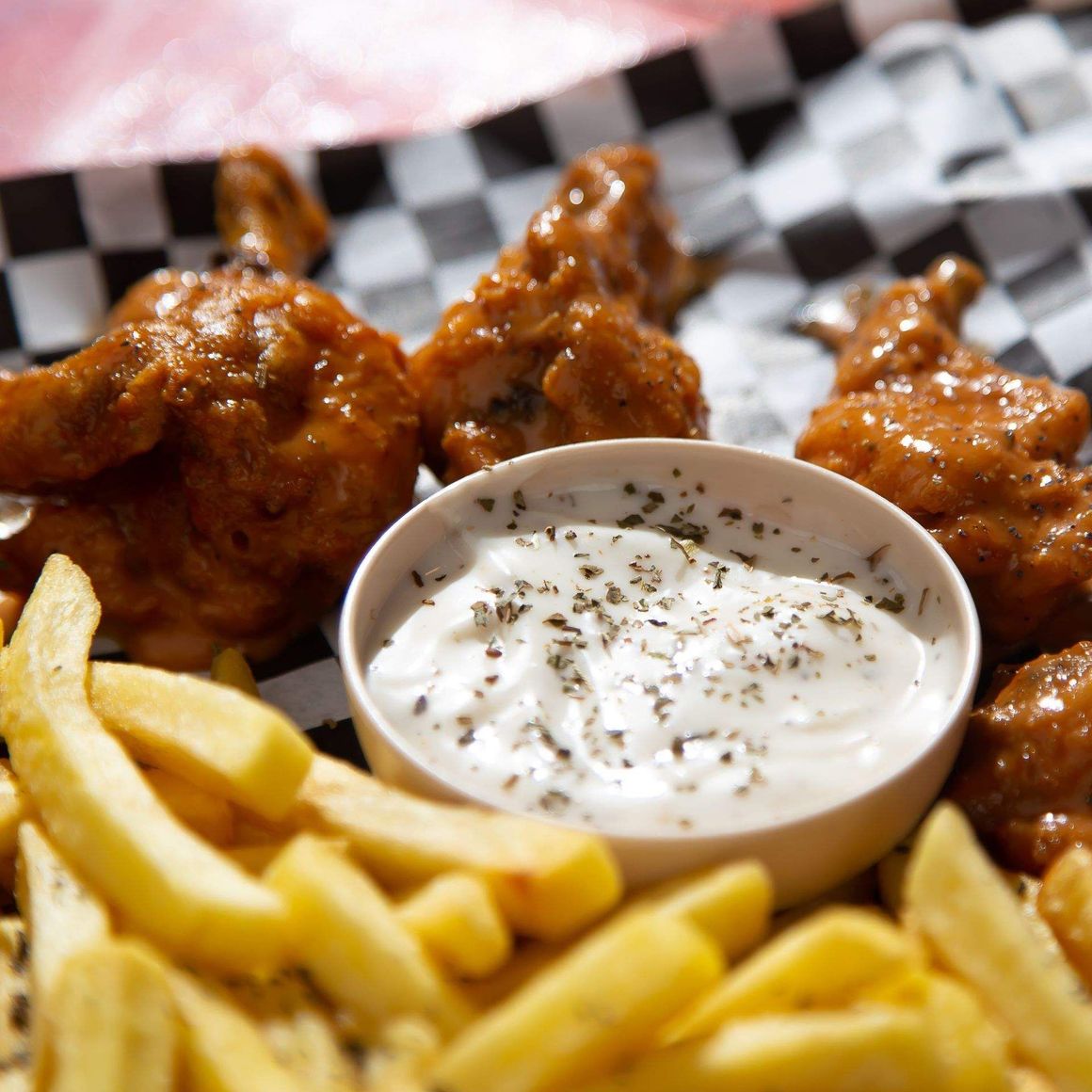 Alitas de pollo y papas fritas con un tazón de crema agria