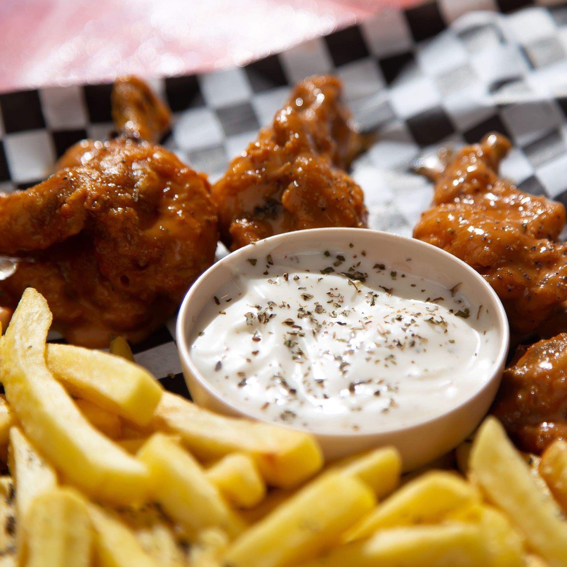 Alitas de pollo y papas fritas con un tazón de crema agria