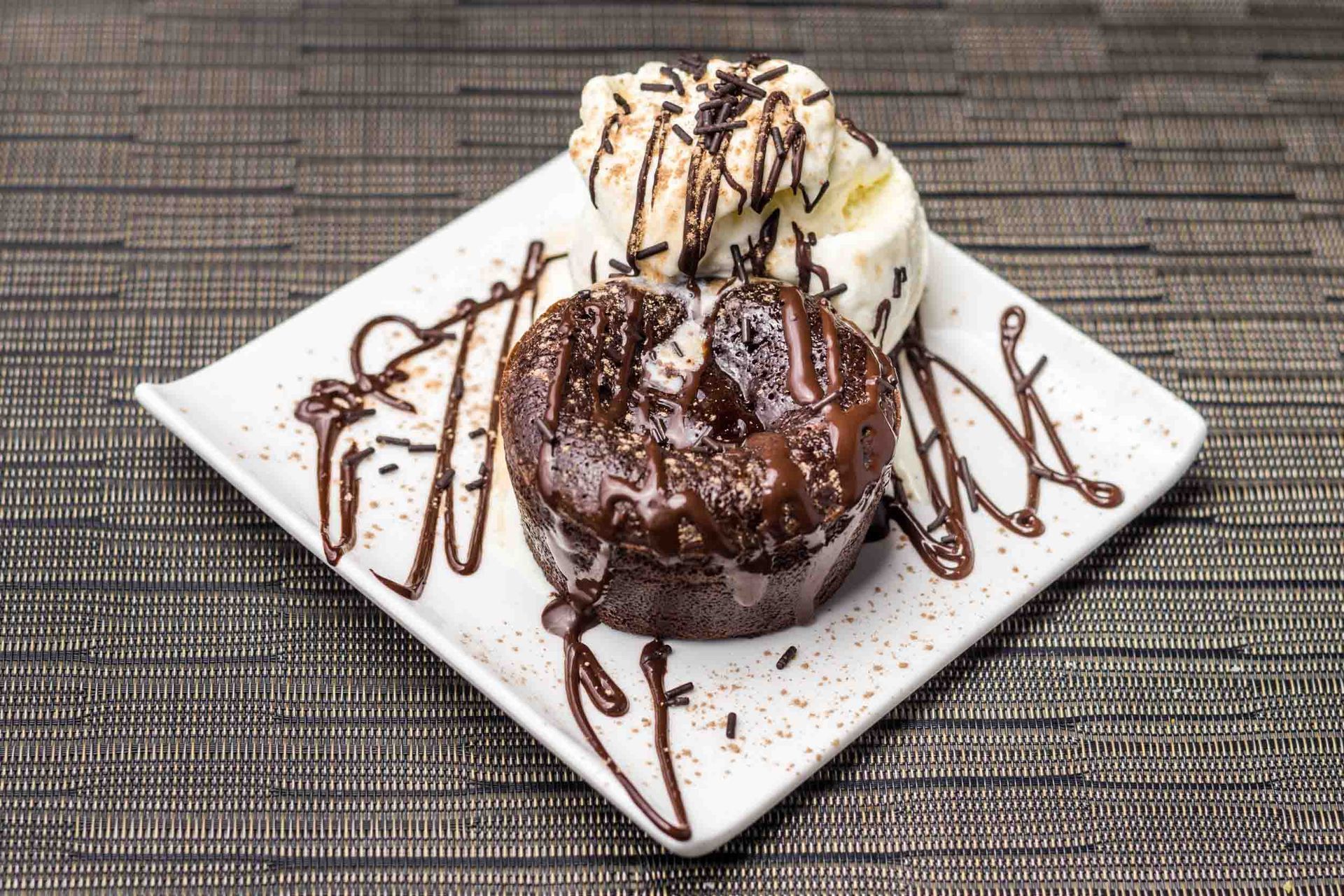 Un plato blanco cubierto con un pastel de chocolate y helado.