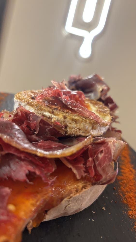 Una persona está poniendo queso en una hamburguesa sobre un pan.