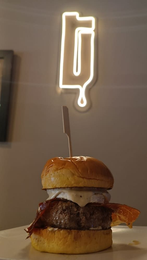 Una persona está poniendo queso en una hamburguesa sobre un pan.