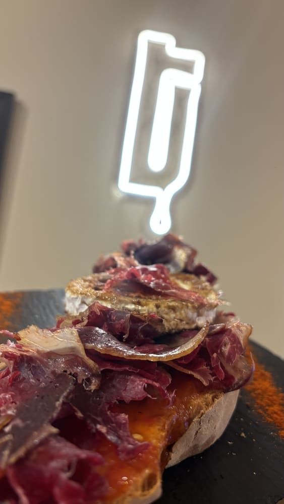 Un postre coronado con frutos rojos y un letrero de neón blanco que brilla al fondo.