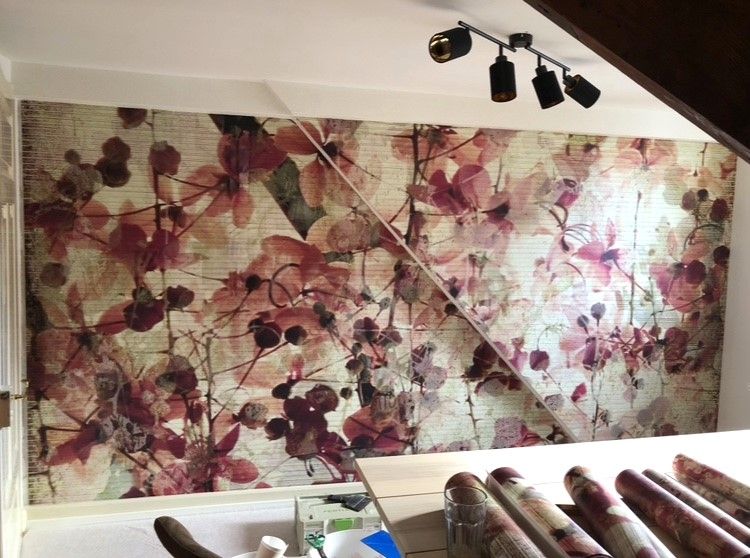 Blumentapeteninstallation mit rosa und roten Blumen unter Schienenbeleuchtung.