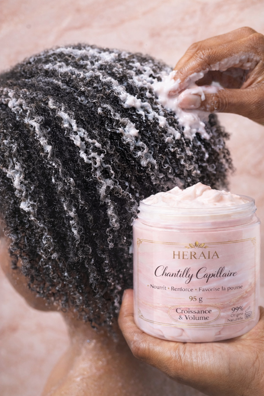 Une personne applique un produit capillaire sur des cheveux texturés avec un pot de produit Chantilly Capellin.