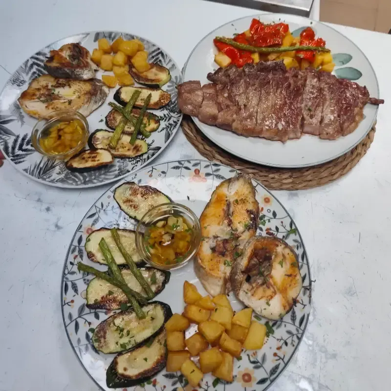 Tres platos de comida: pescado con verduras y patatas; filete con pimientos.