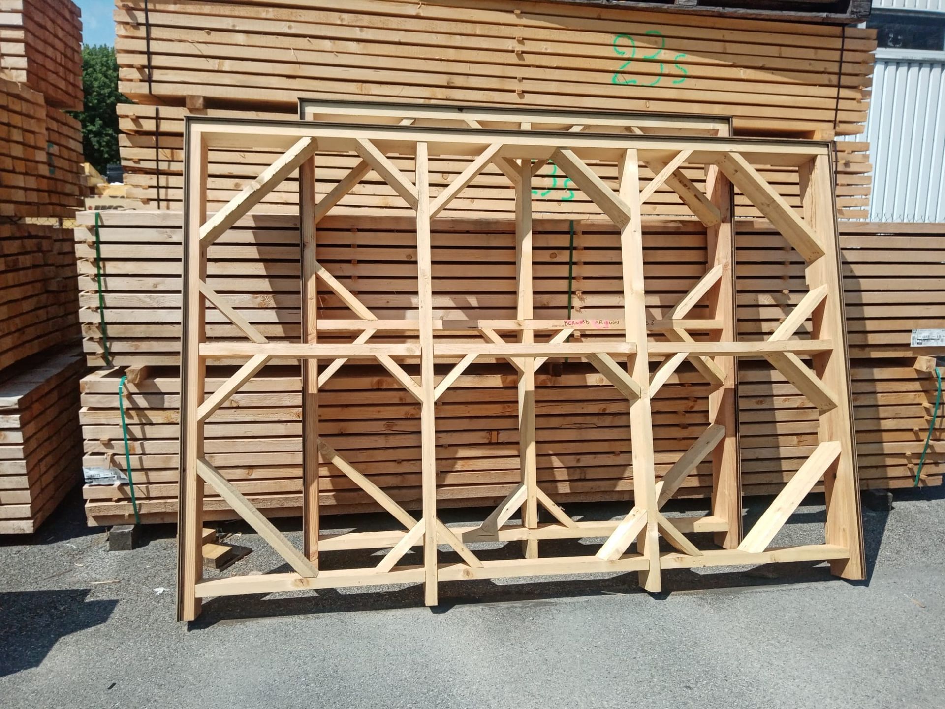 Cadre carré en bois recouvert de grillage, rempli de gravier foncé, sur un sol boueux.