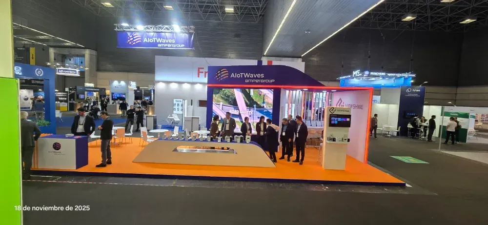 Stand de feria comercial con un expositor de suelo naranja y un arco blanco en un gran pabellón de exposiciones, gente cerca